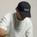 Man in a white tee looking down while wearing the Optimized Workflows black cap