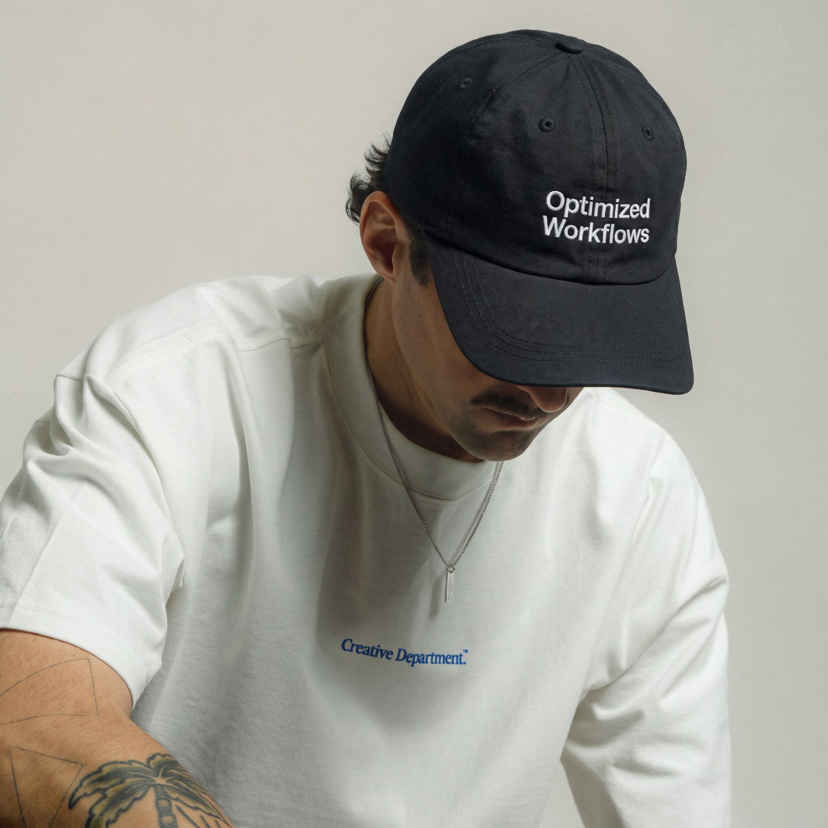 Man in a white tee looking down while wearing the Optimized Workflows black cap