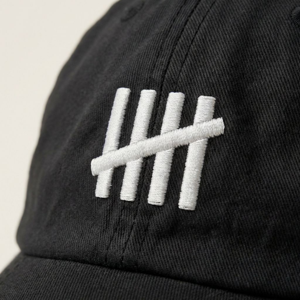 Close-up of The HeadCount tally mark logo embroidered in white on black cotton