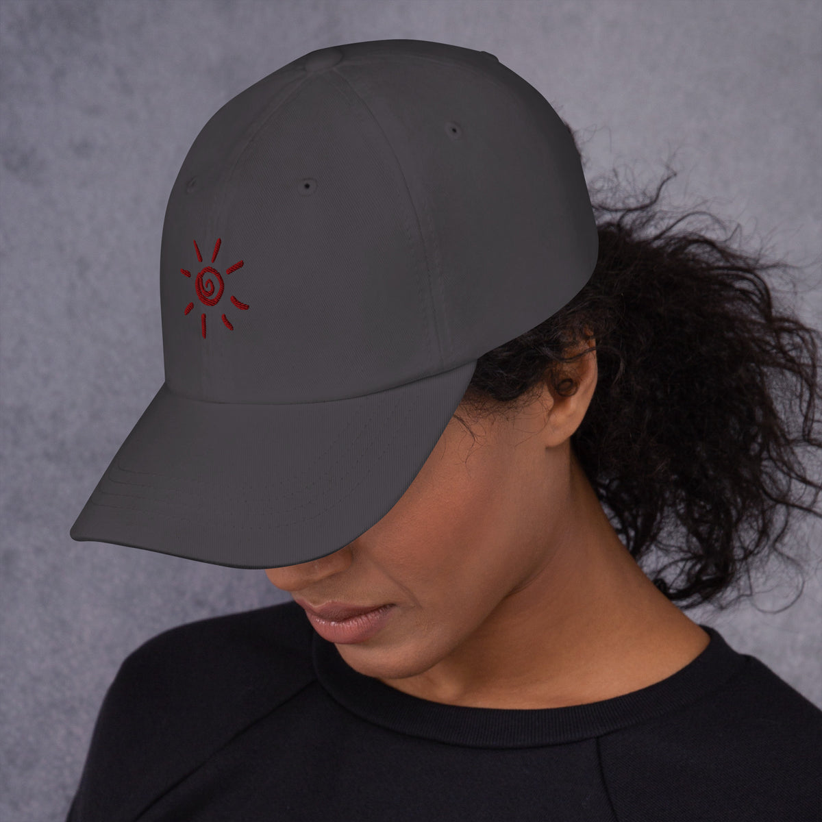 Model wearing the dark grey Sun Cap with terracotta sun embroidery, left side view