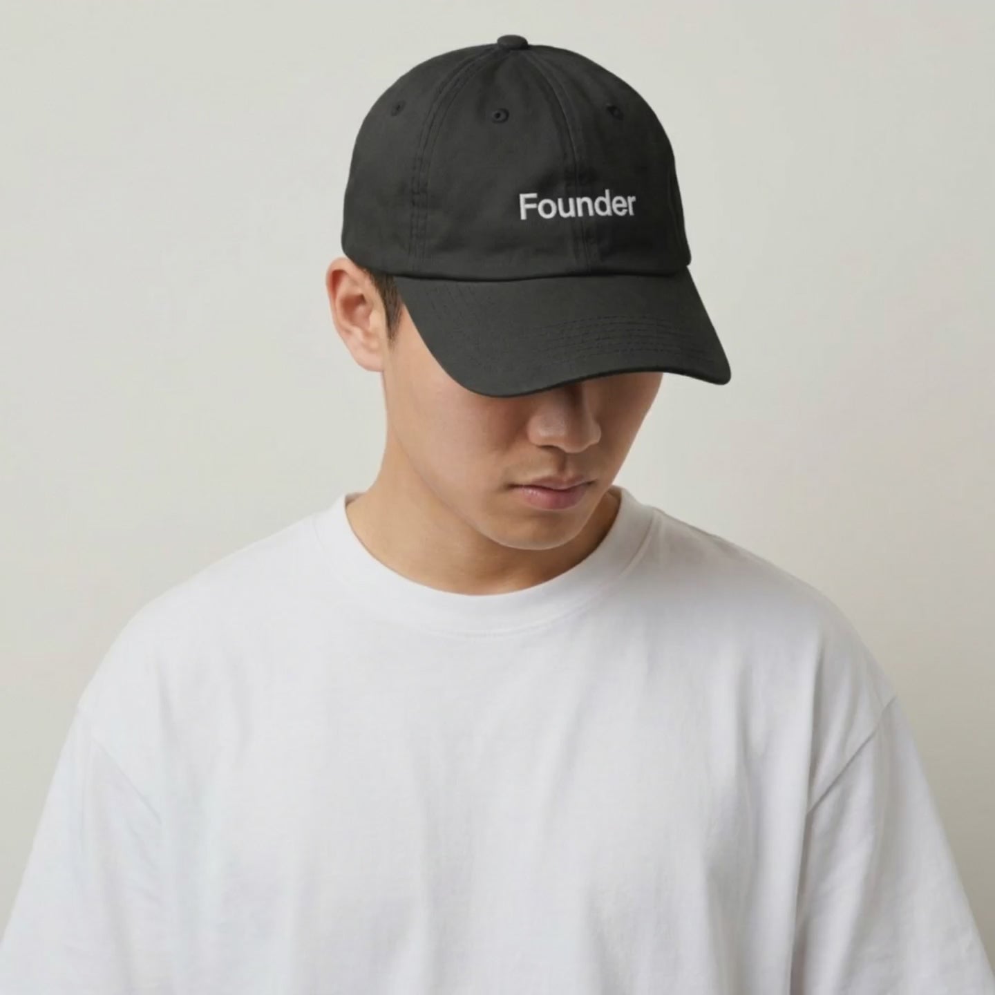 Video: model in a white tee wearing the Founder black cap, head tilted down