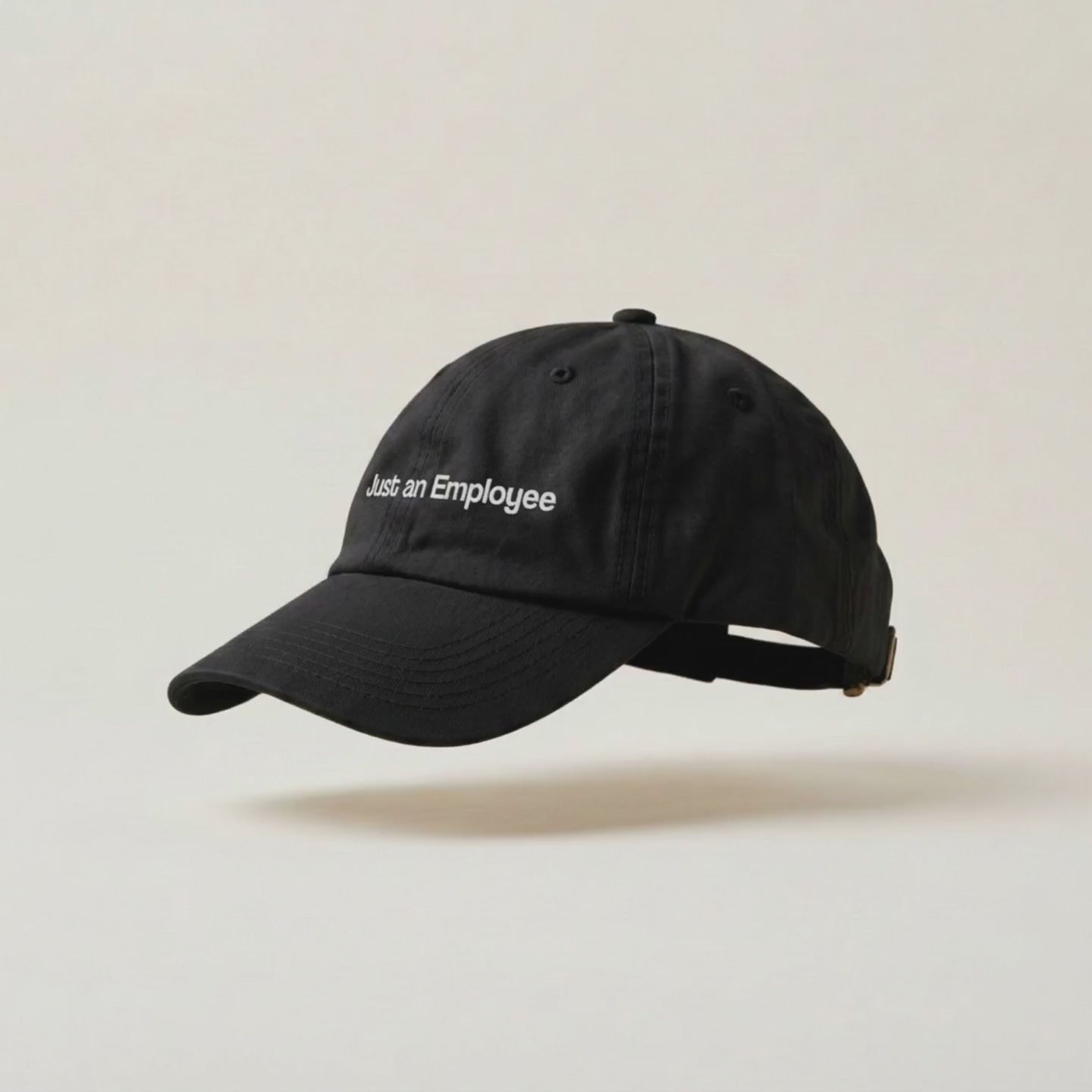Video: the Just an Employee black cap turning slowly on a cream studio backdrop