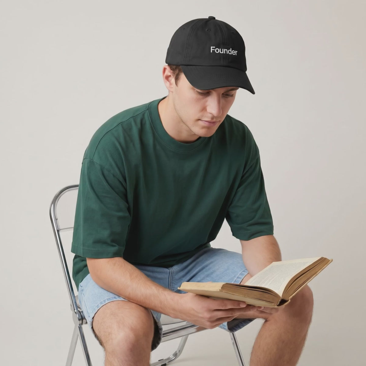 Video: man in a green tee reading a book while wearing the Founder cap